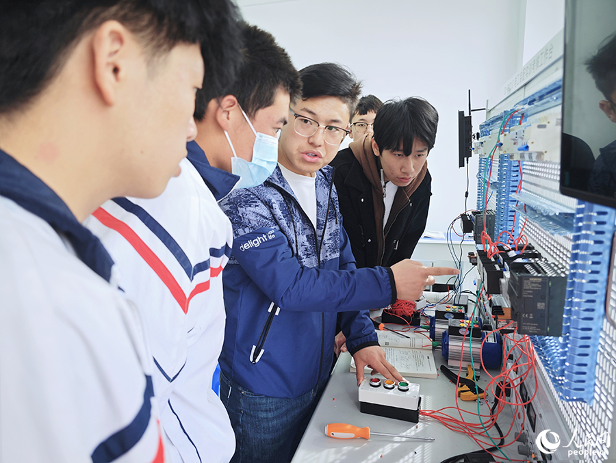 圖為寧夏飛毛腿技工學(xué)校在校生在老師的指導(dǎo)下學(xué)習(xí)基本電路的安裝調(diào)試方法。人民網(wǎng) 黃東儀攝