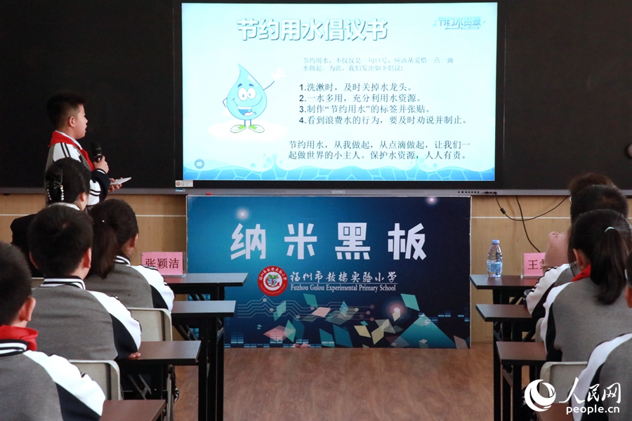 學生們共讀節(jié)約用水倡議書。人民網(wǎng) 葉青卿攝