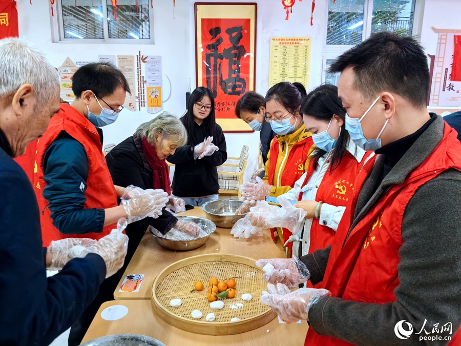 在福州市鼓樓區(qū)屏東社區(qū)長者食堂，老人們正在教年輕人搓芝麻糍。人民網(wǎng) 葉青卿攝