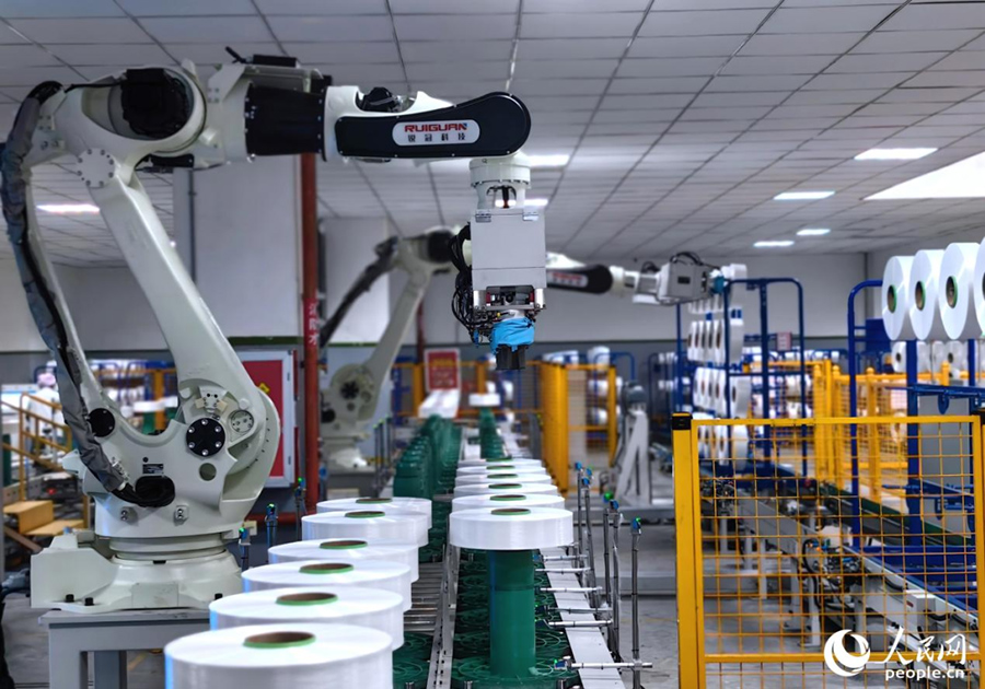 恒申集團(tuán)化纖車間里的機械臂已取代人工進(jìn)行批量搬運。人民網(wǎng) 葉青卿攝