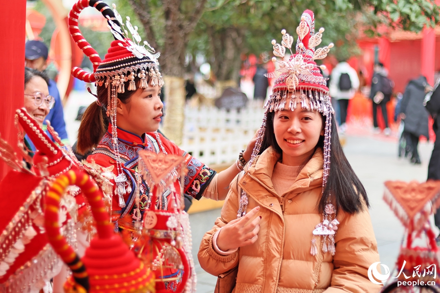 游客（右）體驗(yàn)畬族頭飾。人民網(wǎng) 李昌乾攝