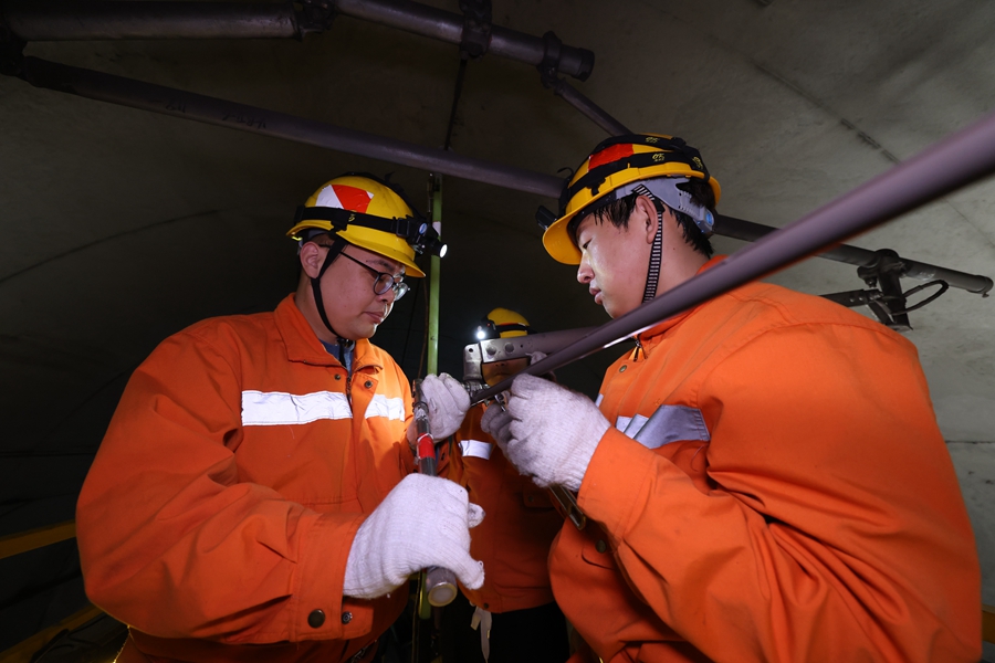 00后接觸網(wǎng)工張烘萊（右一）和工友在檢查接觸網(wǎng)定位裝置。胡鵬攝