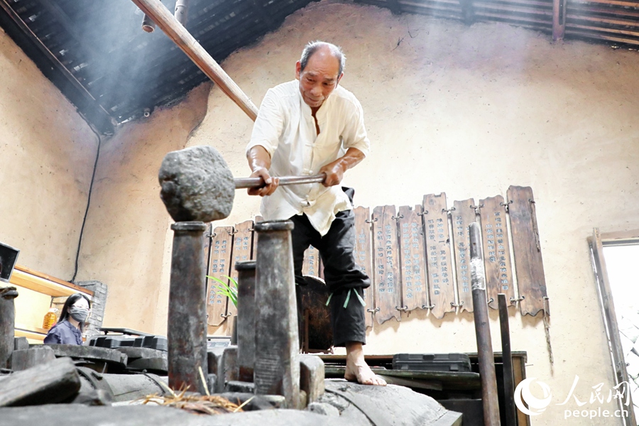 從事古法山茶油制作50年的游信玉現(xiàn)場(chǎng)掄錘榨油。人民網(wǎng) 李唯一攝