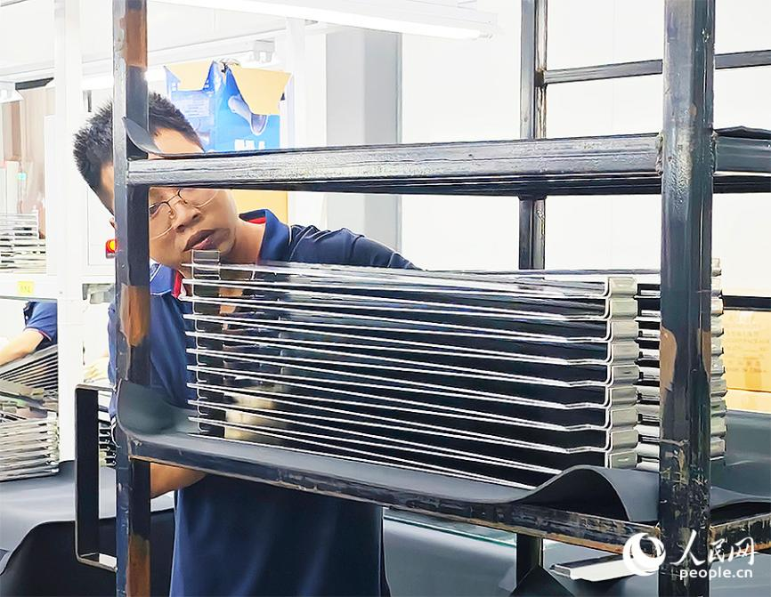 東恒新能源集團廠房內，一名工作人員正將經過質檢的新能源汽車電池模組側板整齊碼放到貨架上。人民網 黃東儀攝