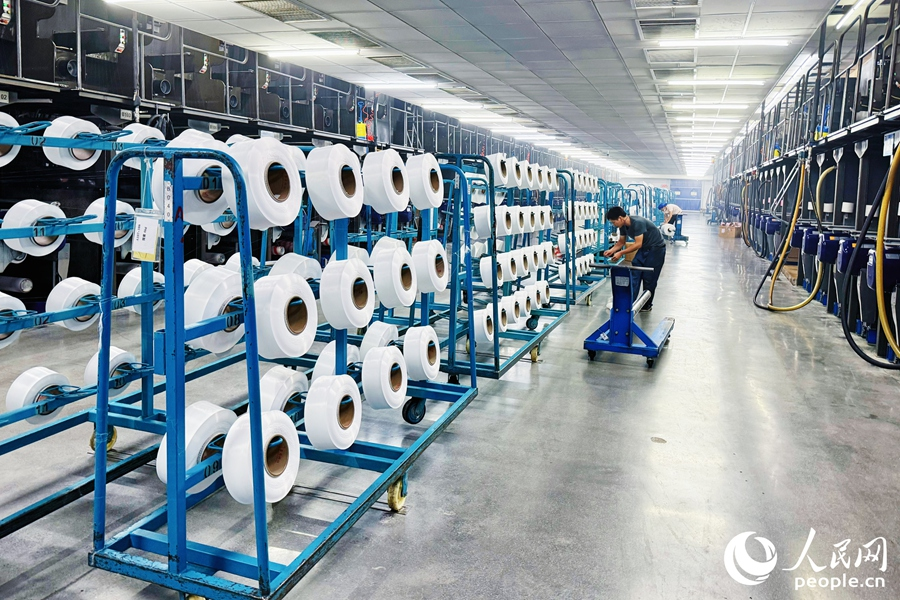 在鑫森合纖的車間里，工人正在檢查已卷繞成型的絲線。人民網(wǎng) 李唯一攝