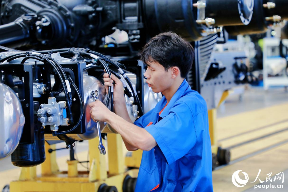 工人將整車底盤的螺絲釘擰緊。人民網(wǎng) 李唯一攝