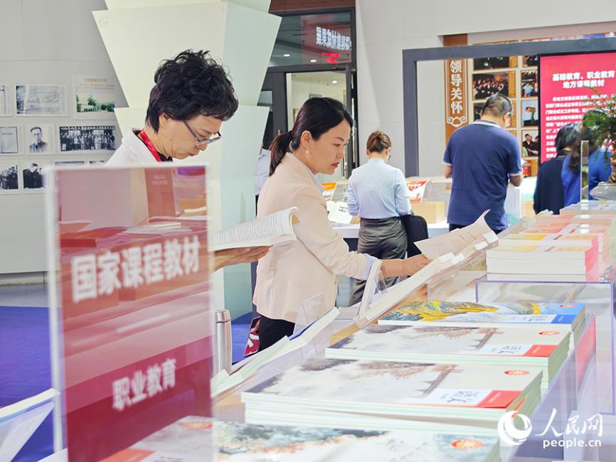 與會(huì)人員參觀成果展。據(jù)統(tǒng)計(jì)，目前中小學(xué)三科統(tǒng)編教材、高校思政課教材已全面融入習(xí)近平總書記地方重大實(shí)踐與重要論述有關(guān)內(nèi)容。人民網(wǎng) 黃東儀攝