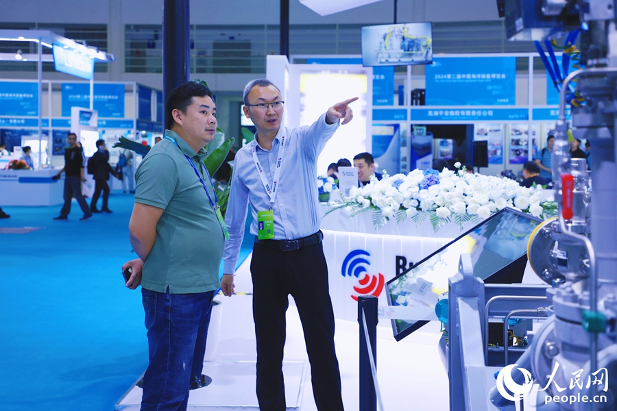 參展商向觀眾介紹迷宮式船用壓縮機有關(guān)情況。人民網(wǎng) 李唯一攝