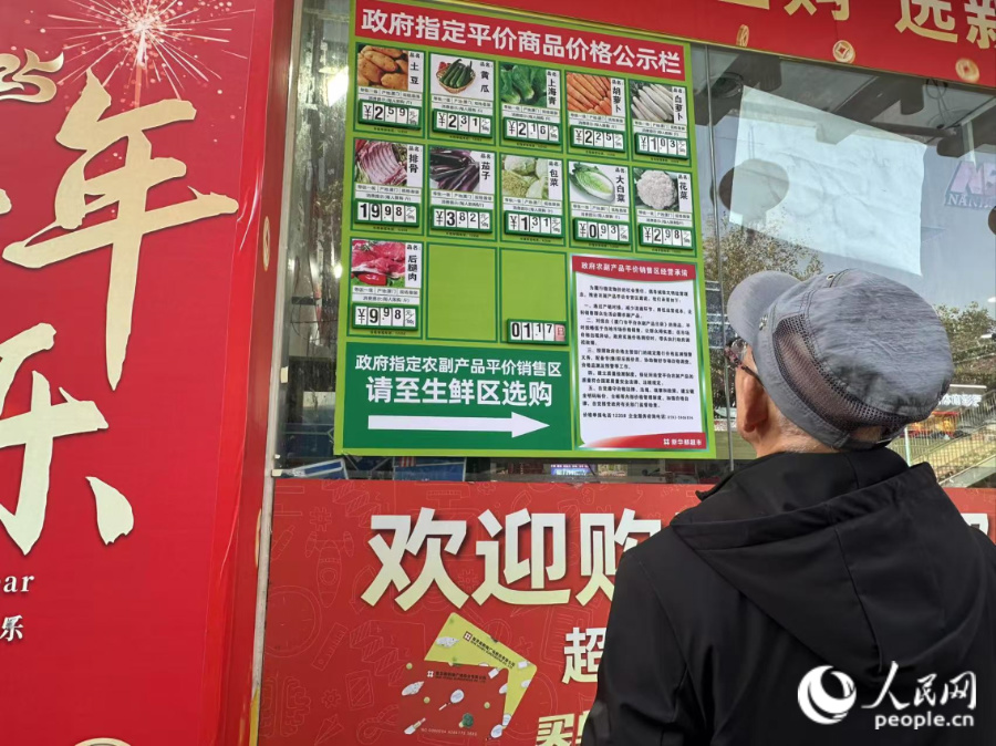 超市門口的價格公示欄標(biāo)注著當(dāng)天售賣的平價肉菜價格。人民網(wǎng)記者 張萌攝