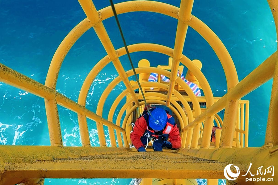 吉榮斌系好安全繩，沿著階梯逐級(jí)爬上平臺(tái)。人民網(wǎng) 李唯一攝