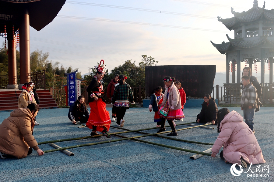 身著傳統(tǒng)服飾的畬族村民和孩子們跳著竹竿舞。人民網(wǎng) 謝星宇攝