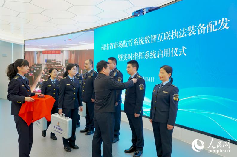 黃水木為執(zhí)法單位代表發(fā)放執(zhí)法裝備。人民網(wǎng) 楊灝昱攝