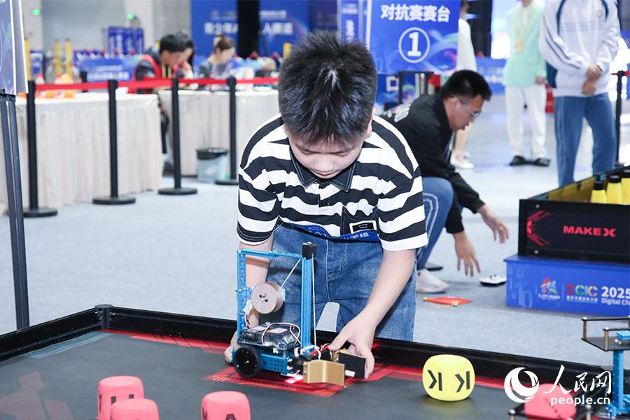 比賽間隙，選手調(diào)整機(jī)器人的位置。人民網(wǎng)記者 焦艷攝