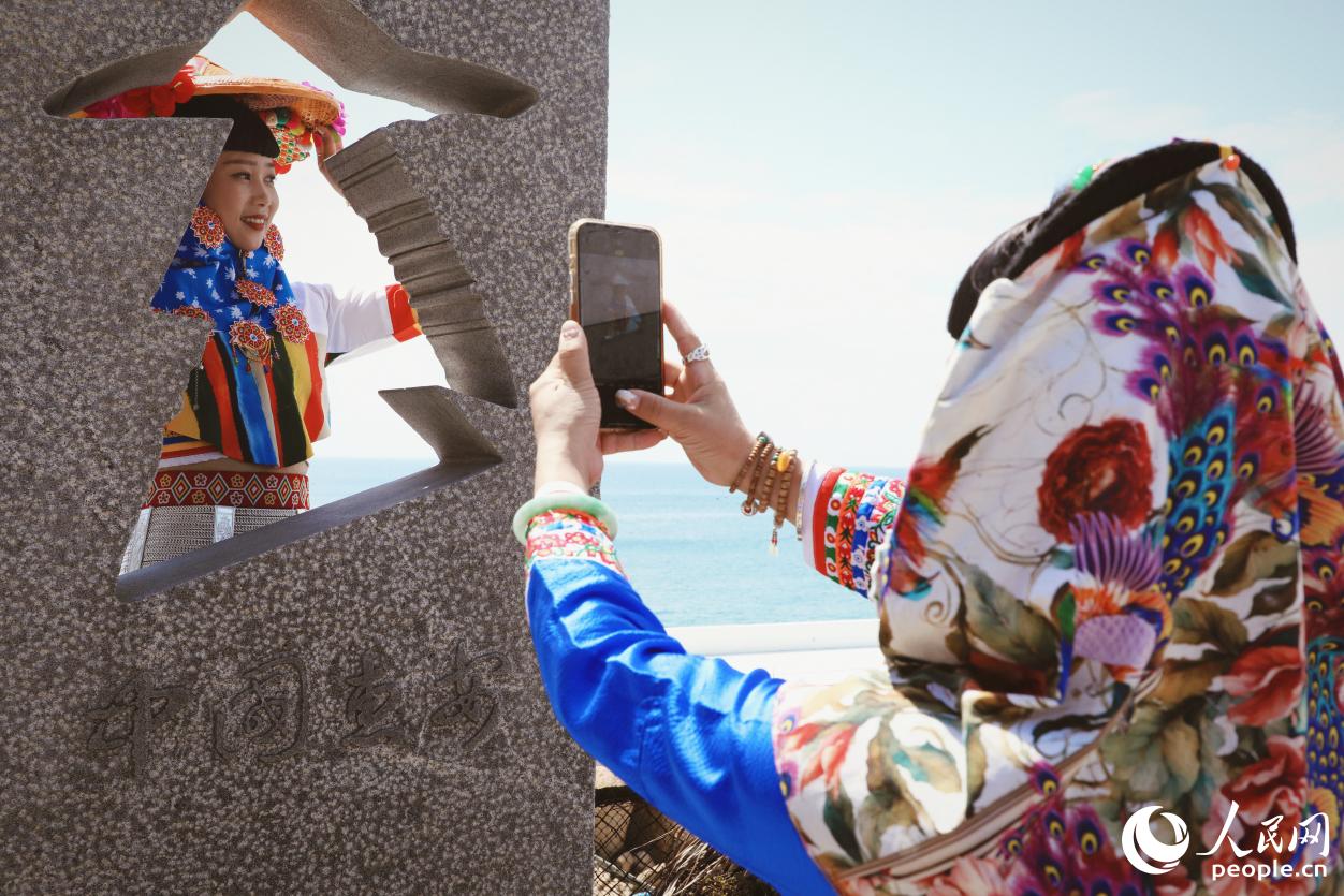 游客身著惠女服飾在海邊“打卡”。人民網(wǎng) 李唯一攝