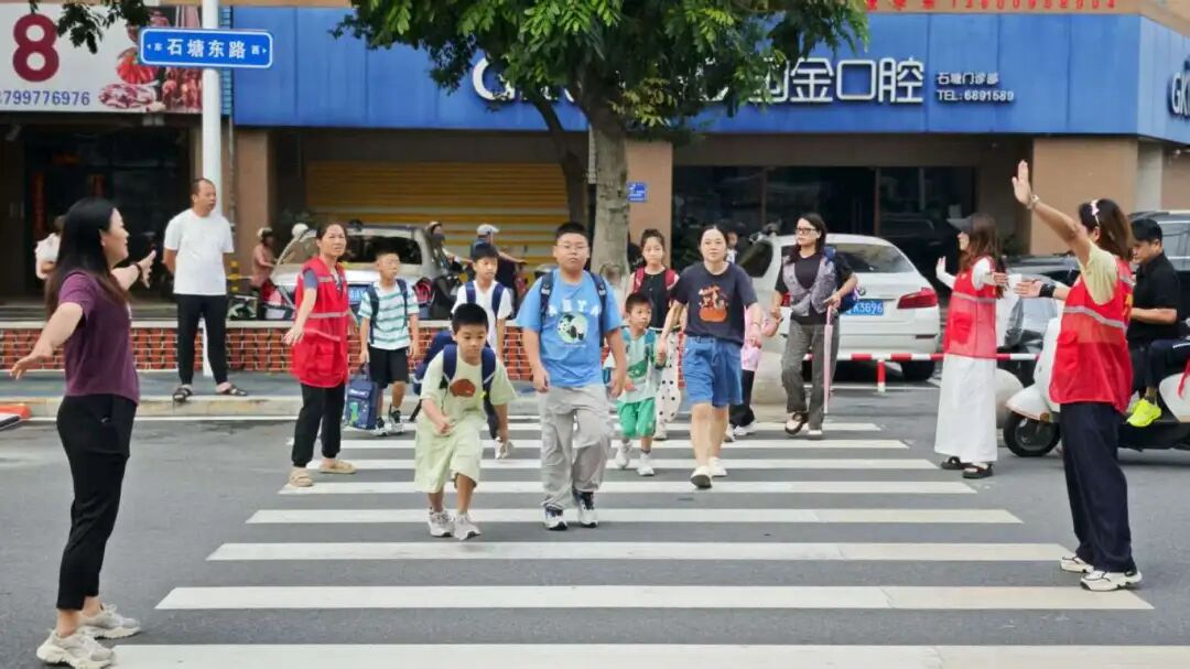 身著紅馬甲的志愿者引導(dǎo)學(xué)生通行