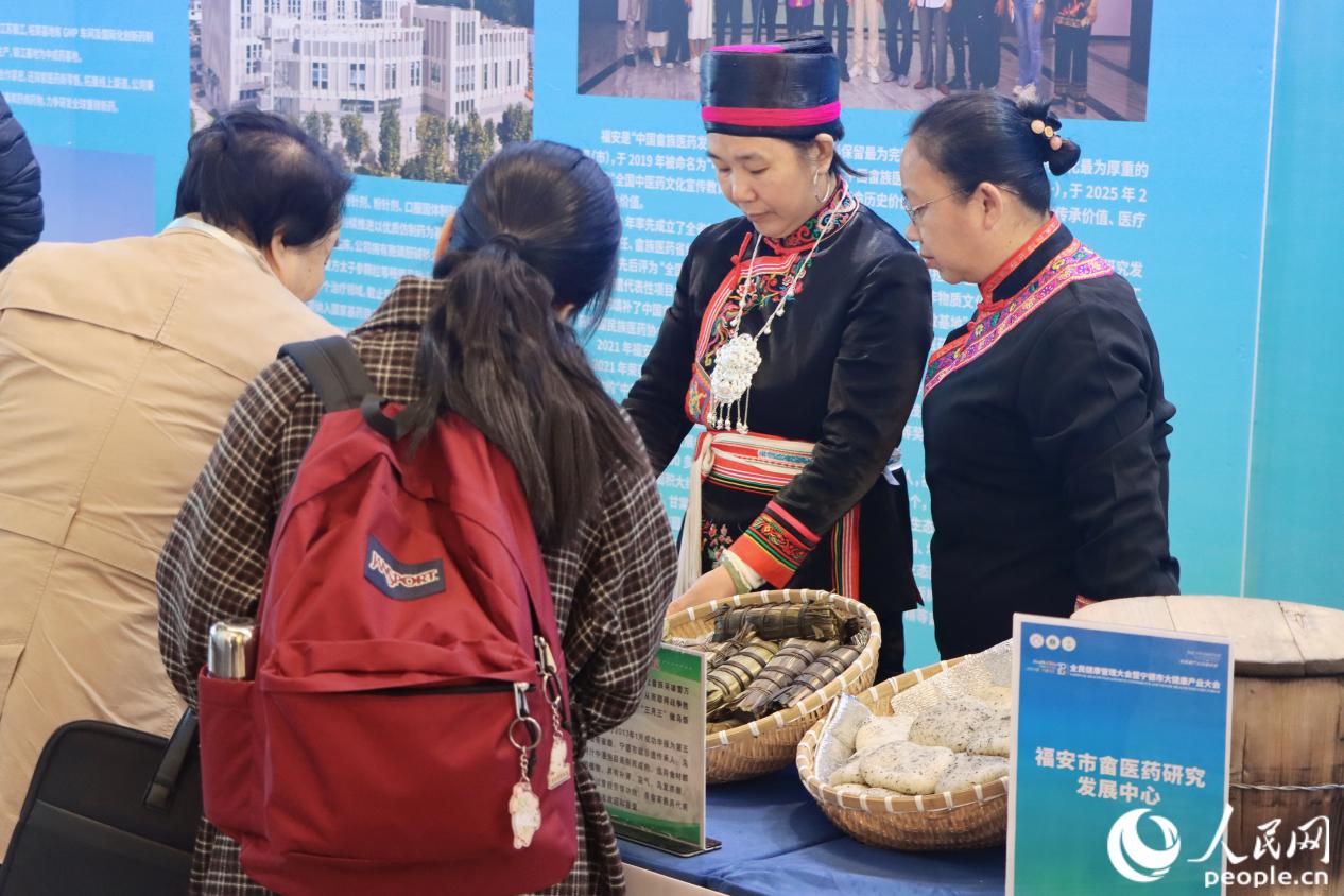 與會嘉賓正在詢問“畬家三寶”——菅粽、烏飯、糍粑。人民網(wǎng) 林銘賢攝