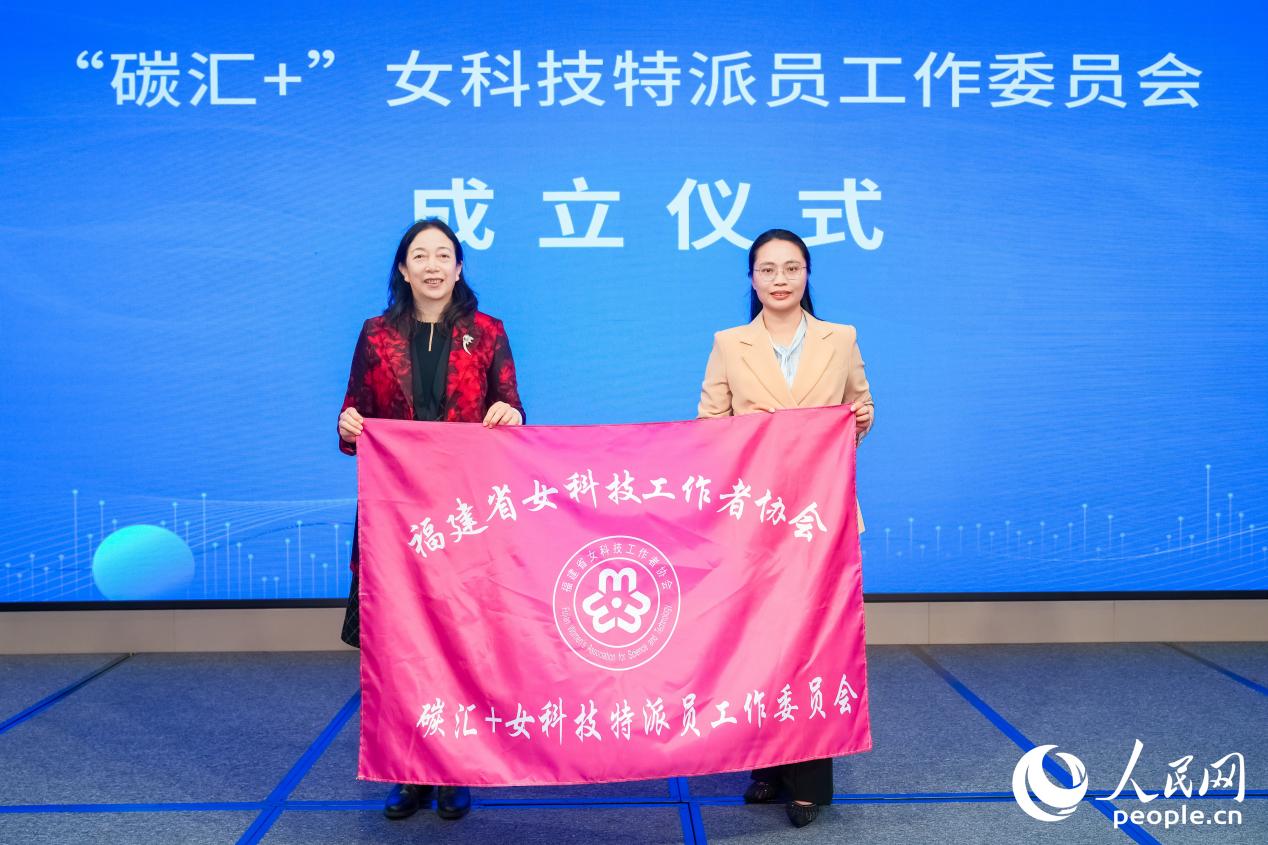 福建省女科技工作者協(xié)會(huì)會(huì)長(zhǎng)許志紅（左）為“碳匯+”女科技特派員工作委員會(huì)授旗。人民網(wǎng)攝