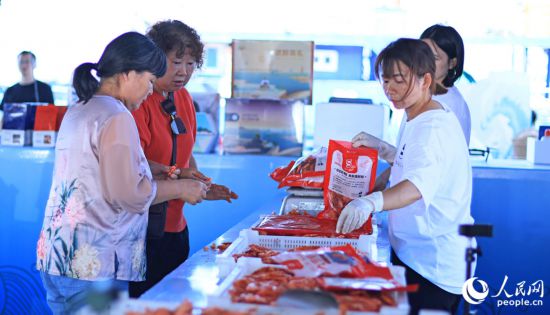 游客在澳角村采購當?shù)睾ｕr加工產(chǎn)品。人民網(wǎng) 李昌乾攝